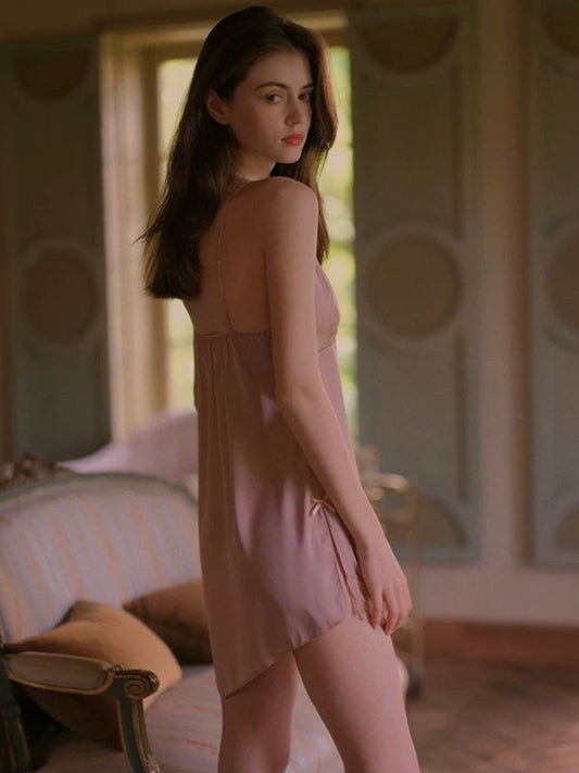 Woman in a pink satin sleep dress standing in a room with a vintage-style interior.