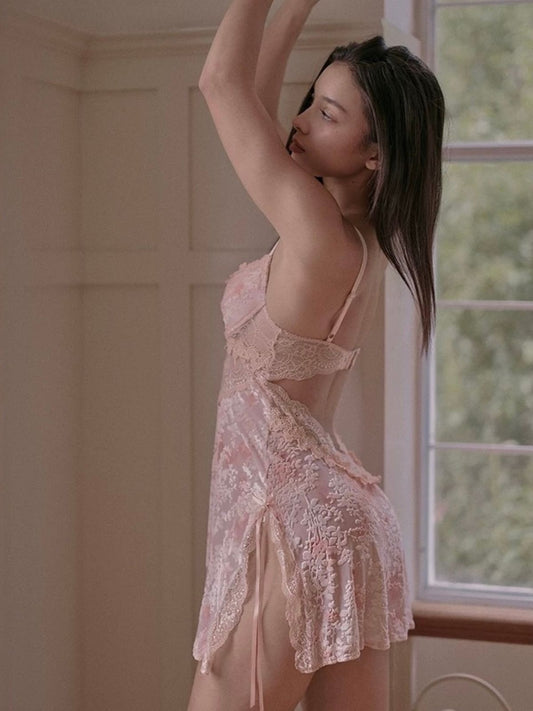 Woman wearing a pink lace nightgown in velvet material in a softly lit room.
