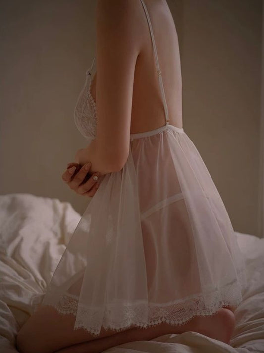 Person wearing a sheer white nightgown with lace details on a neutral background