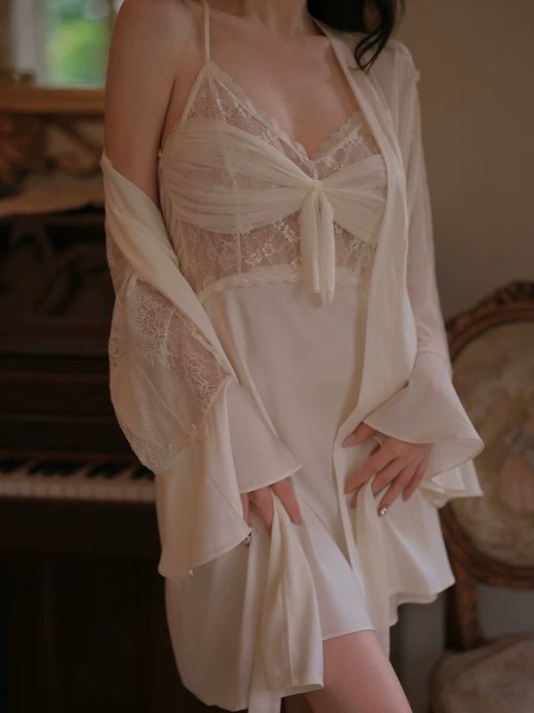 Woman wearing a sheer white lace sexy nightgown with a matching robe in a softly lit room.