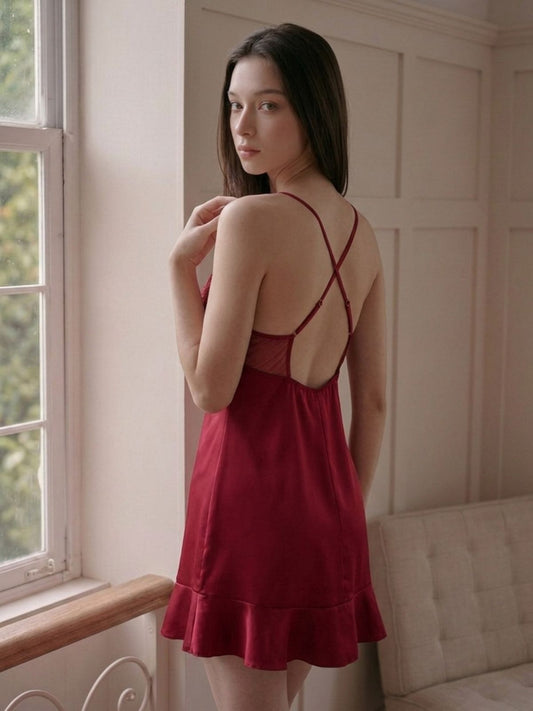 Woman wearing a red dress with thin straps in a softly lit room.