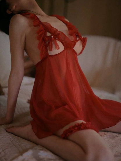 Person wearing a red lace open bust lingerie sitting on a bed.