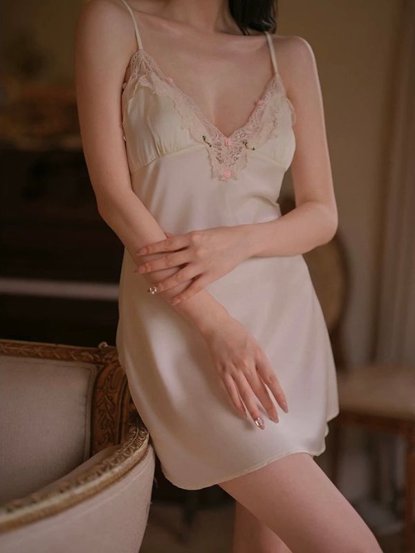 Woman wearing a light-colored lace-trimmed nightgown in a softly blurred indoor setting.