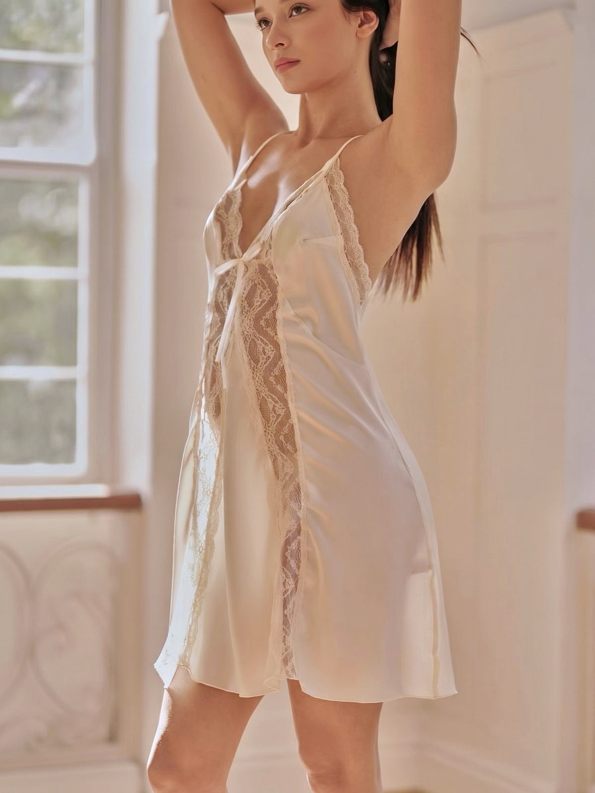 Woman wearing a white lace nightgown in a softly lit room.