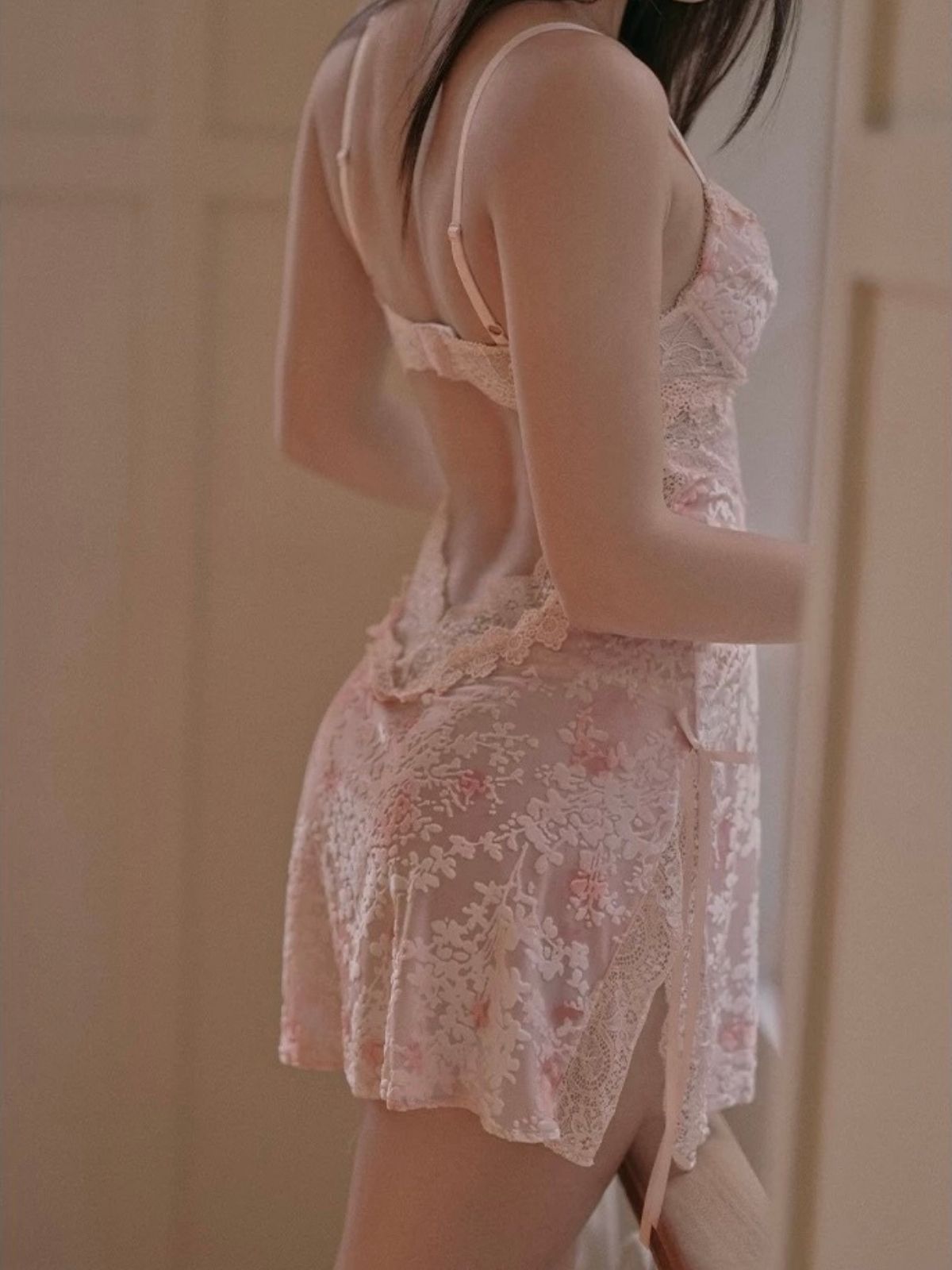 Person wearing a light pink lace outfit with a neutral background
