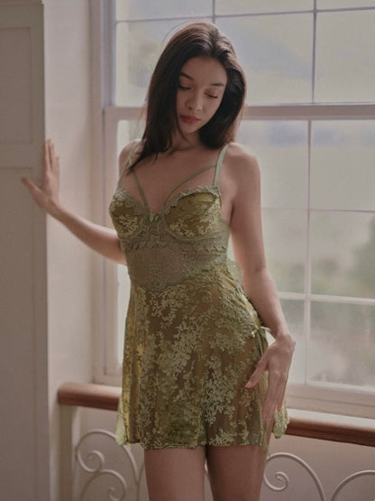 Woman wearing a green lace sleep dress standing in a room with large windows.