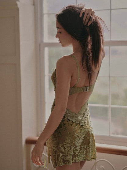 Woman in a green lace dress standing by a window