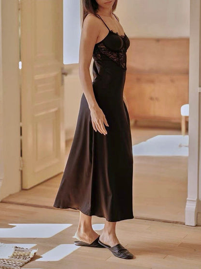 Woman wearing a black slip dress in a room with wooden flooring.