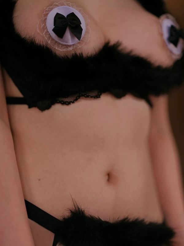 Partial view of a person wearing black fur-trimmed lingerie with decorative elements.
