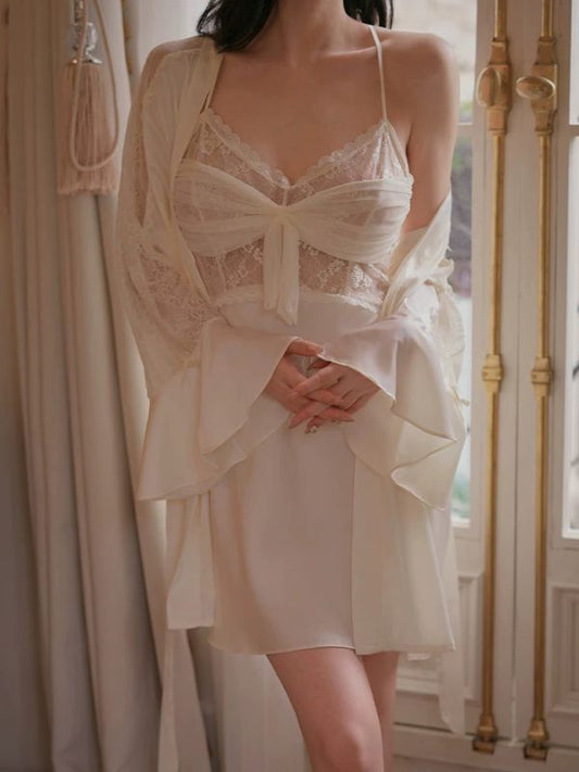 Woman wearing a white lace nightgown with a matching robe in a softly lit room.
