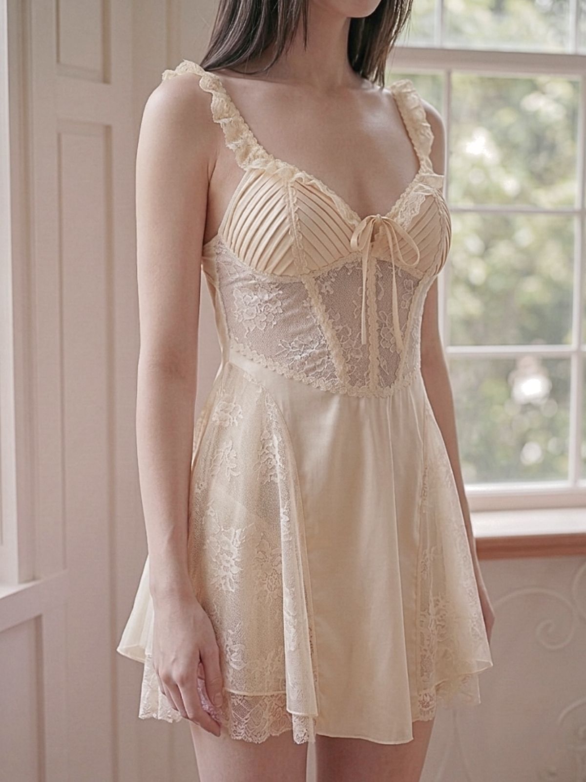 Woman wearing a beige lace nightgown in a softly lit room.