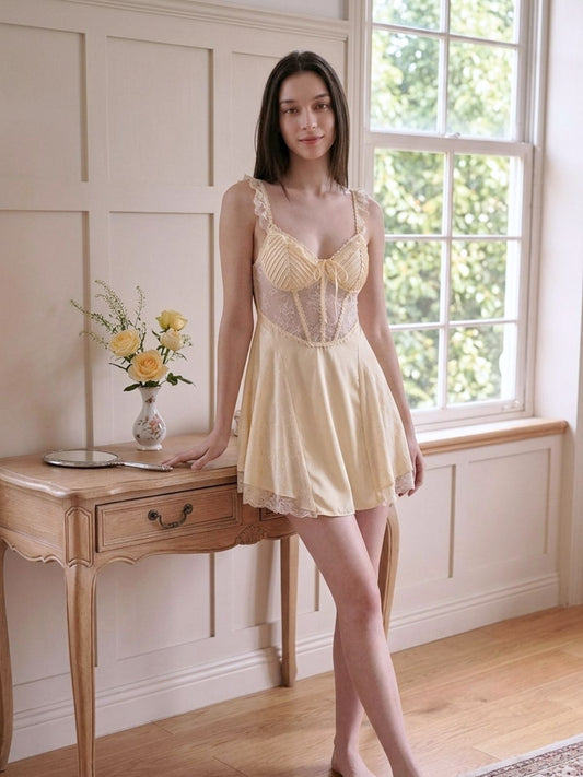Woman in a yellow lace nightgown standing in a room with a window and table.